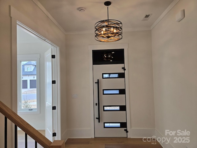 foyer featuring crown molding, wood-type flooring, and a chandelier