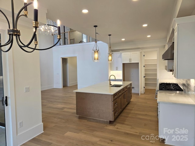 kitchen featuring light wood-type flooring, sink, a center island with sink, and white cabinets