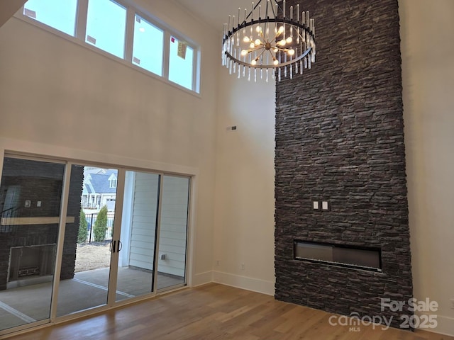 unfurnished living room featuring a healthy amount of sunlight, hardwood / wood-style flooring, a fireplace, and a chandelier