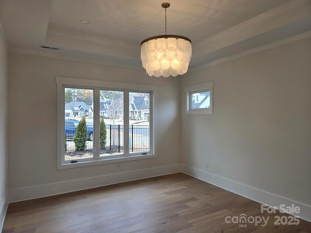 spare room with ornamental molding, wood-type flooring, and a raised ceiling