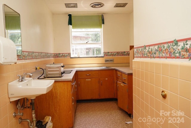 kitchen with a wealth of natural light, tile walls, light tile patterned flooring, and sink