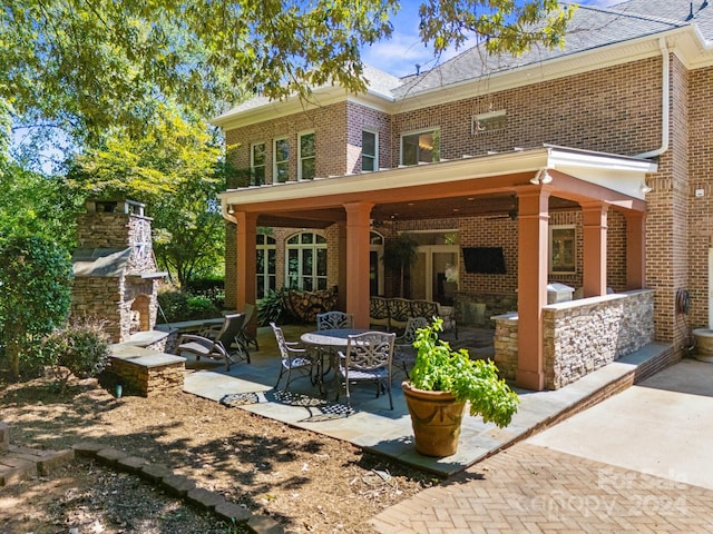 rear view of property with a fireplace and a patio area