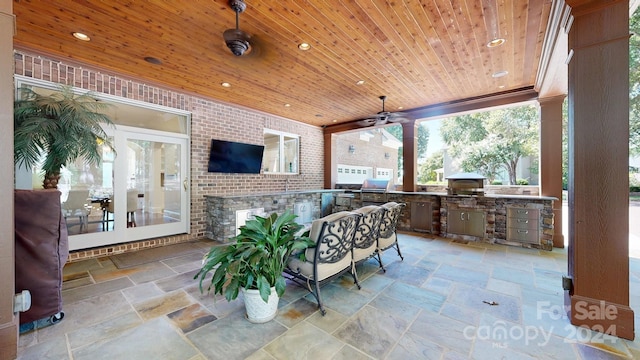 view of patio featuring a grill, ceiling fan, and an outdoor kitchen