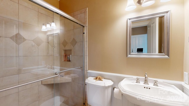 bathroom with sink, a shower with shower door, and toilet