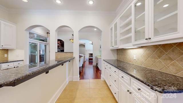 kitchen featuring light hardwood / wood-style flooring, dark stone countertops, white cabinetry, and tasteful backsplash