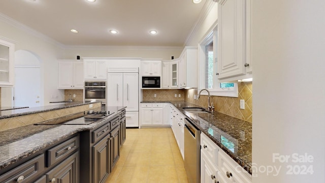 kitchen featuring white cabinets, sink, tasteful backsplash, black appliances, and dark stone counters