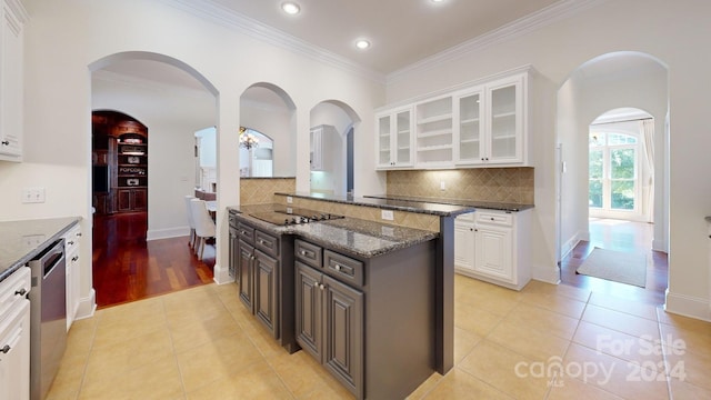 kitchen with dark stone countertops, white cabinetry, light hardwood / wood-style floors, and stainless steel dishwasher