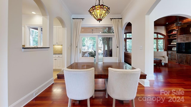 dining area featuring ornamental molding, ceiling fan with notable chandelier, and dark wood-type flooring