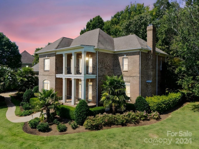 view of front facade featuring a balcony and a lawn