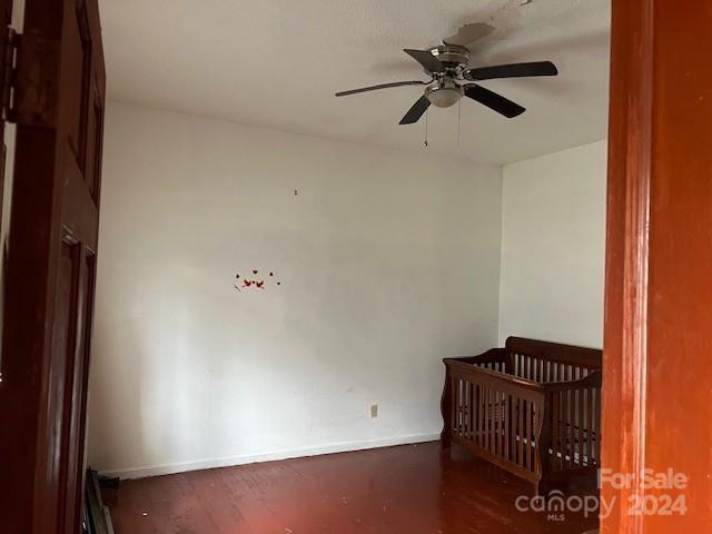 unfurnished bedroom featuring ceiling fan and a nursery area