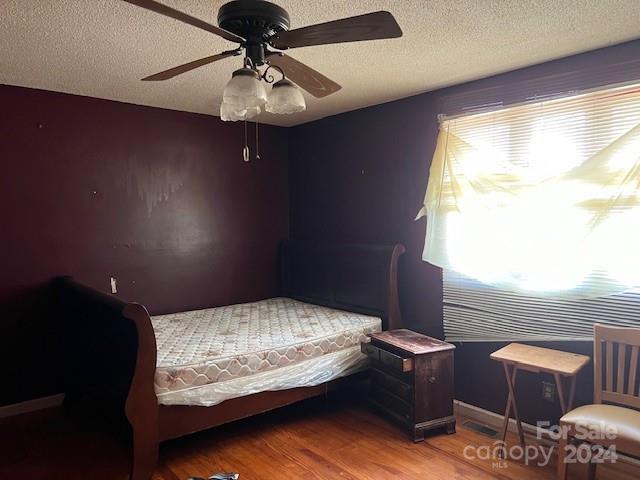 bedroom featuring ceiling fan, wood-type flooring, and a textured ceiling