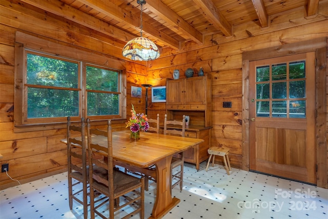 dining space with wood walls, beam ceiling, and wood ceiling