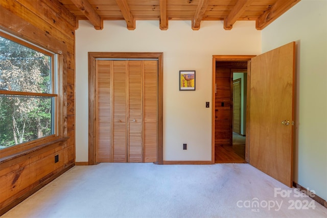 unfurnished bedroom featuring light colored carpet, a closet, wood ceiling, and multiple windows