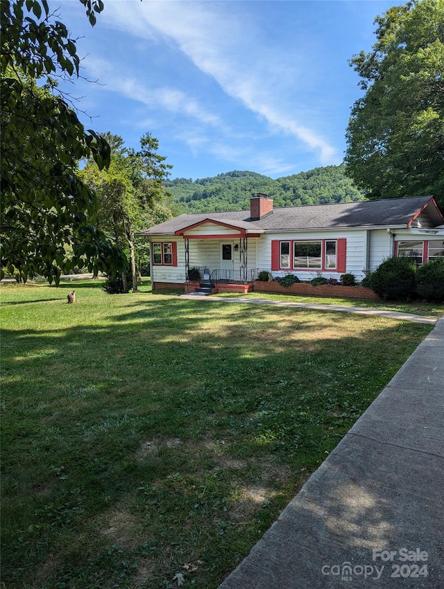 ranch-style house featuring covered porch, a mountain view, and a front yard