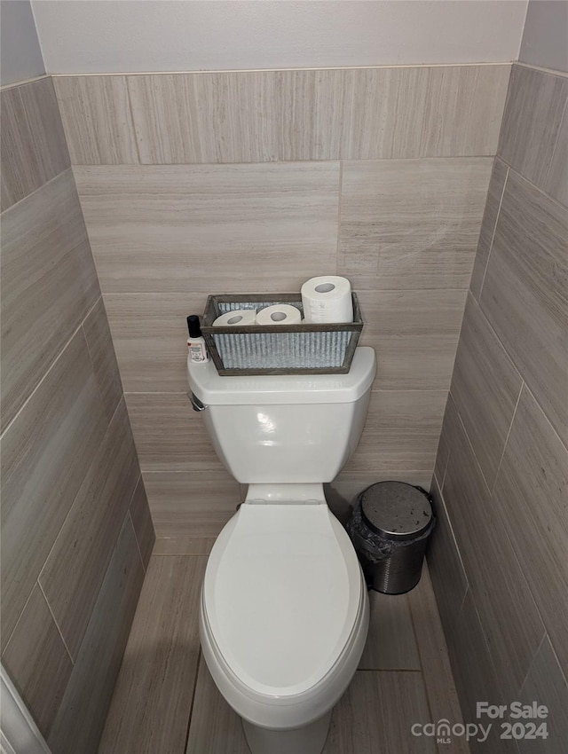 bathroom with tile walls and toilet