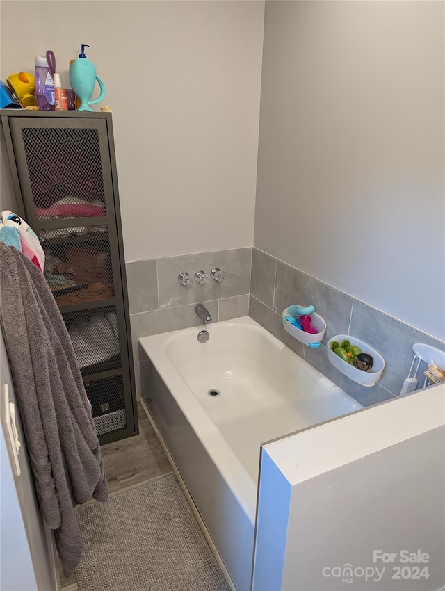 bathroom with a tub and hardwood / wood-style floors