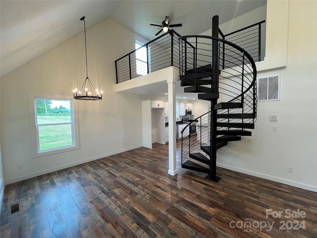 stairway with high vaulted ceiling, ceiling fan with notable chandelier, and hardwood / wood-style floors