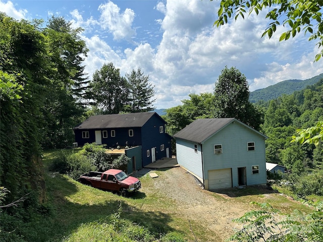 rear view of property with a mountain view, a yard, and a garage