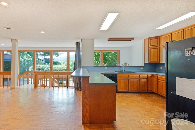 kitchen with black appliances, kitchen peninsula, sink, and light parquet floors