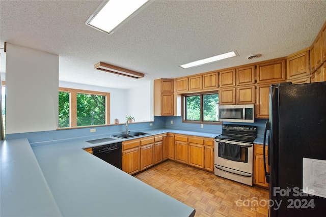 kitchen with kitchen peninsula, a textured ceiling, sink, black appliances, and light parquet flooring