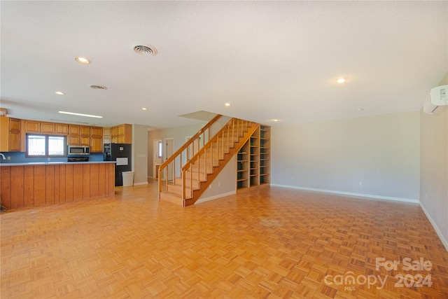 unfurnished living room featuring a wall mounted AC and light parquet floors