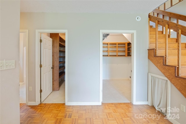 hallway with light parquet floors and a textured ceiling