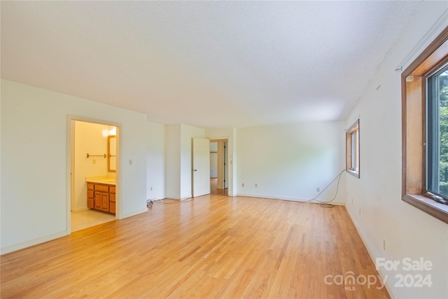 unfurnished room with a textured ceiling, light hardwood / wood-style flooring, and a wealth of natural light