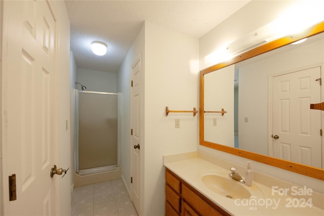 bathroom featuring a shower with door, vanity, and a textured ceiling