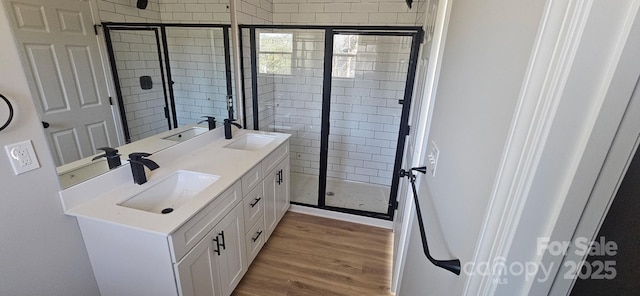 full bath featuring double vanity, wood finished floors, and a sink