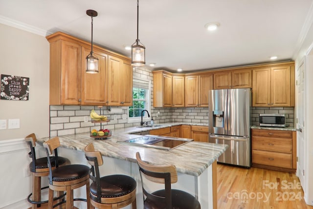 kitchen featuring a kitchen breakfast bar, kitchen peninsula, hanging light fixtures, and stainless steel appliances