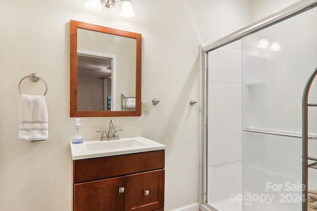 bathroom featuring a shower with door and vanity