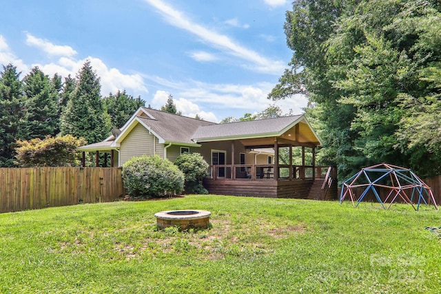 rear view of property featuring a yard, a deck, and an outdoor fire pit