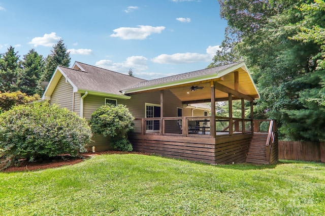 rear view of property featuring ceiling fan and a yard