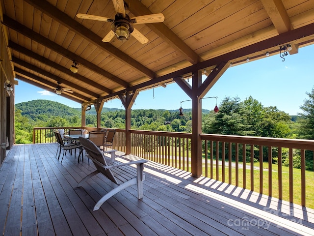 wooden deck with ceiling fan, a lawn, and a mountain view