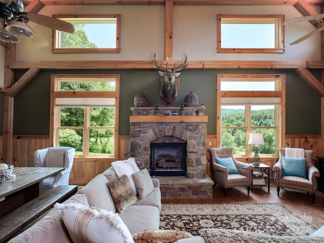 living room featuring ceiling fan, hardwood / wood-style flooring, and a stone fireplace