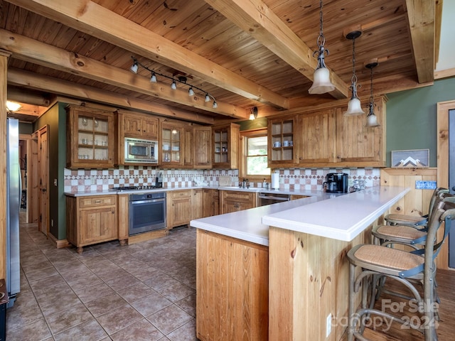 kitchen featuring kitchen peninsula, appliances with stainless steel finishes, backsplash, a kitchen breakfast bar, and pendant lighting