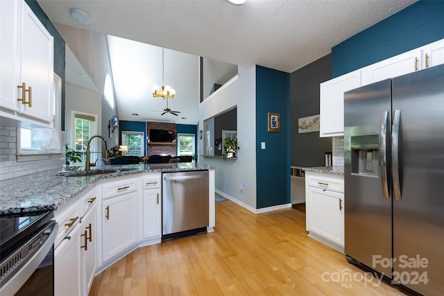 kitchen with backsplash, white cabinets, ceiling fan with notable chandelier, hanging light fixtures, and appliances with stainless steel finishes