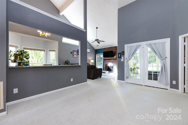 living room with a high ceiling, ceiling fan with notable chandelier, and a brick fireplace