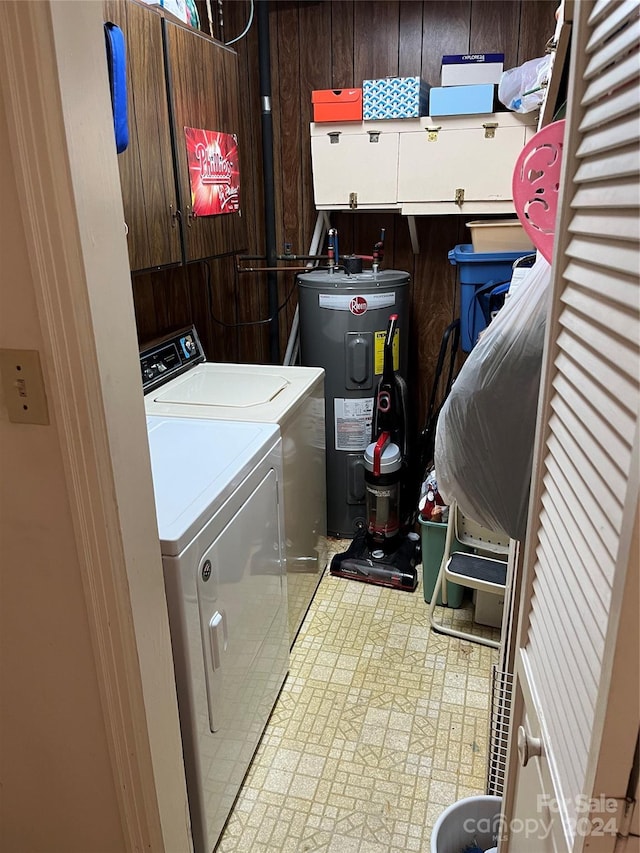 laundry room featuring electric water heater, wood walls, and independent washer and dryer