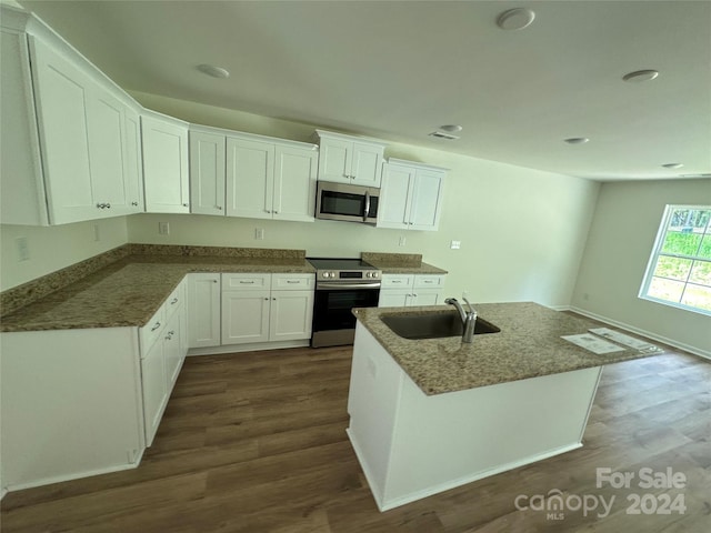 kitchen featuring appliances with stainless steel finishes, white cabinets, sink, a center island, and dark wood-type flooring