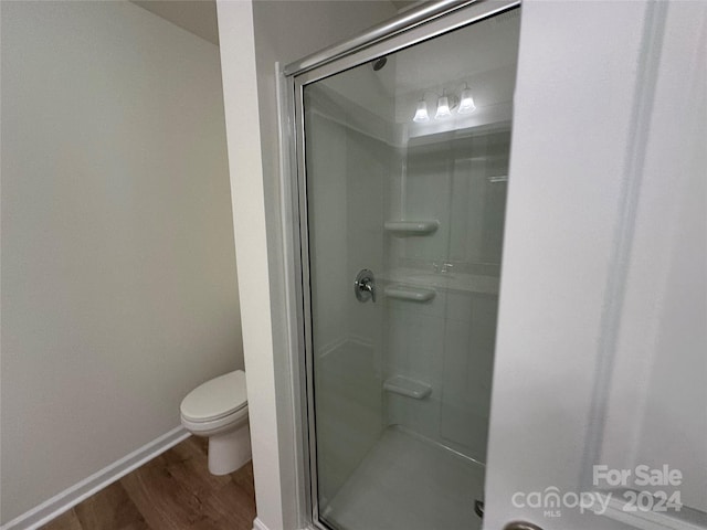 bathroom with a shower with shower door, toilet, and hardwood / wood-style floors