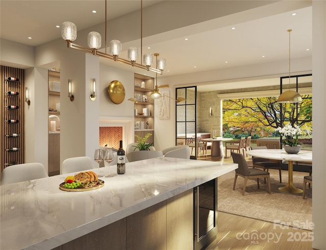 kitchen with light stone counters, hanging light fixtures, and light hardwood / wood-style flooring