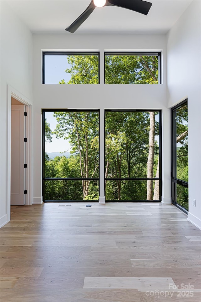 interior space with a towering ceiling, light wood finished floors, and a ceiling fan