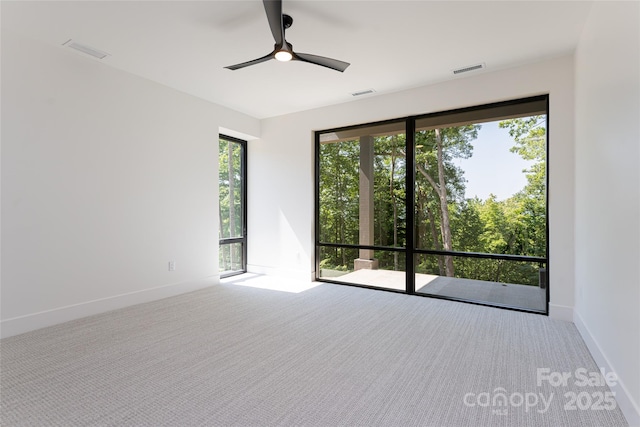 carpeted empty room featuring a ceiling fan, visible vents, and baseboards