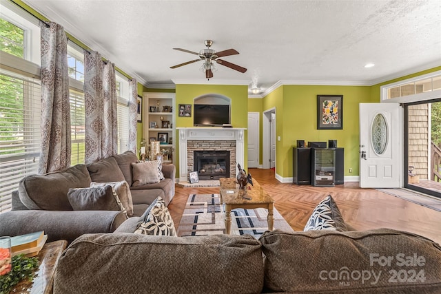 living room featuring a stone fireplace, plenty of natural light, a textured ceiling, and parquet flooring