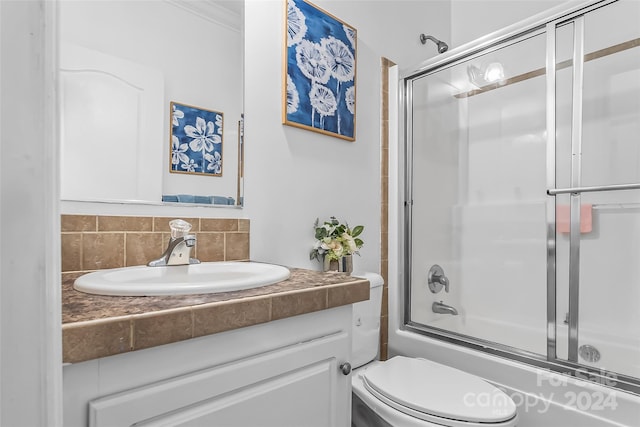 full bathroom with decorative backsplash, ornamental molding, vanity, shower / bath combination with glass door, and toilet