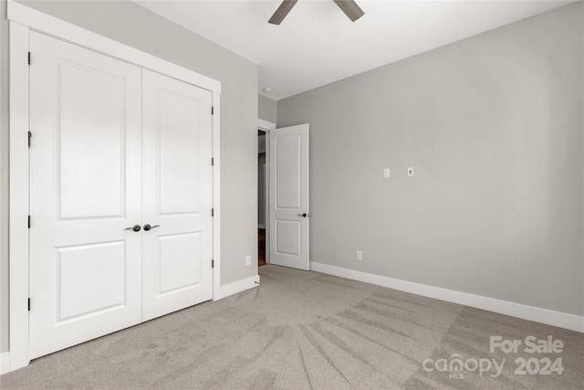 unfurnished bedroom featuring light carpet, a closet, and ceiling fan