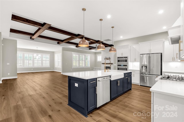 kitchen with coffered ceiling, white cabinetry, blue cabinets, appliances with stainless steel finishes, and light hardwood / wood-style floors