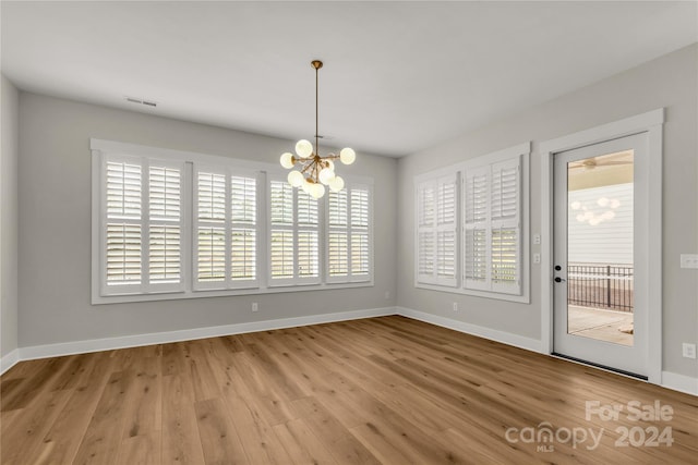 unfurnished dining area featuring a notable chandelier, light hardwood / wood-style floors, and plenty of natural light