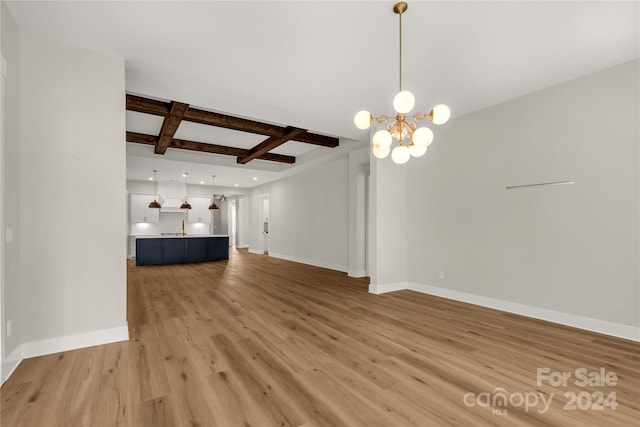 unfurnished living room featuring coffered ceiling, beamed ceiling, sink, a notable chandelier, and light hardwood / wood-style floors